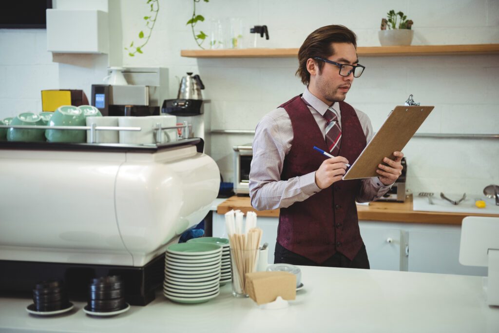 Gerente de restaurante organizando documentos e verificando checklist em um ambiente de cozinha profissional